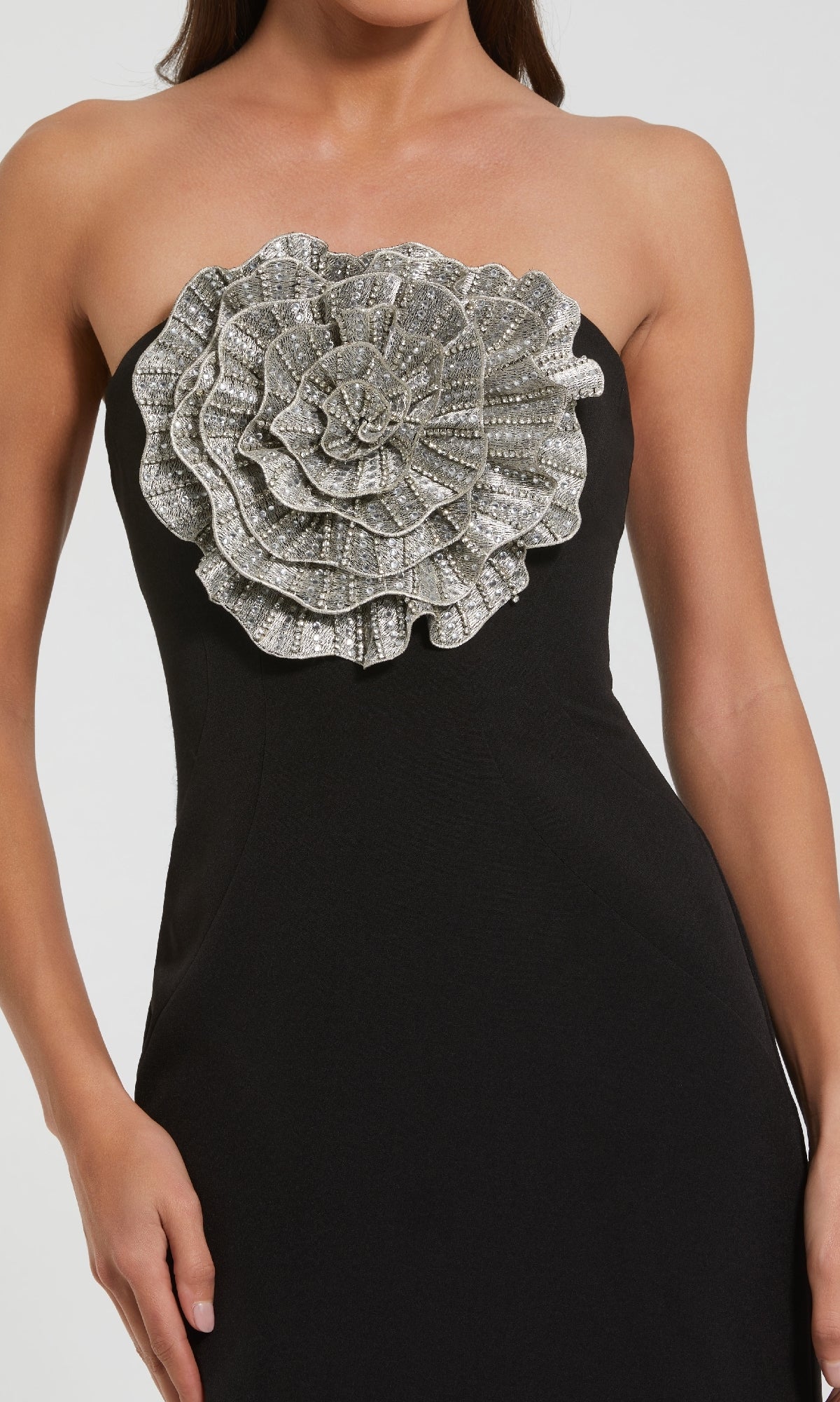 Black strapless dress with a large silver floral embellishment on a white background